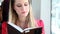 Blond young woman sitting in tram, reading book