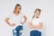 Blonde angry mom and sad daughter in white t-shirts and jeans isolated on white background