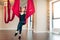 Blonde antigravity yoga instructor standing in empty studio with red hammock.