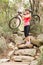 Blonde athlete carrying her mountain bike over rocks