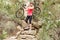 Blonde athlete carrying her mountain bike over rocks