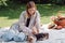Blonde beautiful girl sitting on white blanket in garden and having picnic at sunny day with cute puppies.