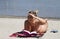 Blonde in a bikini.On the beach.Sand.It lies on a towel.She holds a book in his hand.