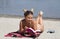 Blonde in a bikini.On the beach.Sand.It lies on a towel.She holds a book in his hand.