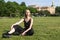 Blonde in black clothes and glasses sits in a clearing in a Park in Saint Petersburg against the background of the Mikhailovsky