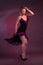 Blonde, in black Spanish Dressdress flamenco dancer in action, on a Burgundy background of the Studio