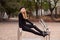 A blonde in a black sweater and beret is sitting on a ramp for the disabled people