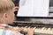 Blonde boy 5 years old, preschooler playing the piano, view from the back