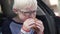 A blonde boy eats a burger in a car at a stop during a road trip