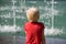 Blonde boy in the red shirt looks at the fountain. Back view