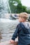 Blonde boy standing at a fountain