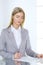 Blonde business woman examining contract while sitting at the glass desk in office background . Lawyer or secretary