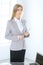 Blonde business woman standing straight and holding tablet in office background. Lawyer or secretary specialist at work