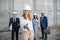 Blonde businesswoman in helmet ready for handshake and colleagues standing behind