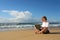 Blonde businesswoman sits with notebook on beach