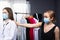 The blonde buyer and brunette consultant, both wearing medical mask. The female client asks for help. Pandemic concept. Indoor