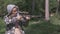 Blonde in a camo jacket is shooting from a crossbow. Slow motion. Closeup