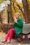 Blonde candid attractive young smiling woman on bench in autumn park with coffee