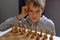 Blonde caucasian boy thinking of a next chess move Playing chess. Strategy, planning concept