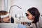 Blonde Caucasian female child looking ahead while sitting in front of the optometrist