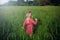 Blonde Caucasian girl in pink rustic dress walking in tall grass on meadow at sunset