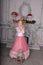 Blonde with curls in hairstyle princess in white and pink elegant dress in the interior