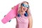Blonde with curly hair in a pink t-shirt. A happy young lady with a pink skateboard, blue headphones and sunglasses