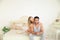 Blonde cute woman and hispanic man sitting in bad in morning.