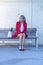 Blonde executive wearing red jacket sitting on a city bench while looking away