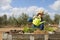 Blonde farmer woman with a green watering can. She is watering a small planting before it can be transplanted into the vegetable