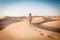 Blonde female Caucasian traveler leaving footprints in sand dunes when walking in dessert in Oman