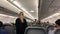 A blonde female flight attendant checking the passengers before a flight