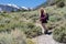 Blonde female hiker walks uphill on a trail in California`s Eastern Sierra Nevada Mountains