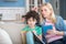 Blonde female holding tablet, checking what curly boy writing in his notebook