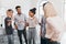 Blonde female manager in glasses and ripped jeans telling joke to colleagues before presentation. Indoor portrait of