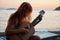 Blonde female playing acoustic guitar on the beach