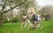 Blonde female riding city bicycle with baby in bicycle chair