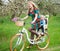 Blonde female riding city bicycle with baby in bicycle chair