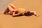 Blonde girl in bikini upside view lies on back on wet sand