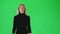 Blonde girl in black turtleneck and grey skirt going against green screen. Slow motion