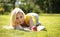 Blonde Girl with Book and Apple lying on Green Grass