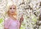 Blonde Girl with Cherry Blossom. Spring Portrait. Beautiful Young Woman with Sakura. Outdoor