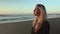 A blonde girl enters the frame, removes her mask and enjoys the fresh sea air and looks at the sunset. Slow motion.