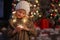 a blonde girl examines a Christmas garland in her hands and smiles against