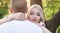 The blonde girl faces the camera and hugs the guy by the neck