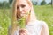 Blonde girl in field picking daisy in hand