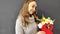 A blonde girl in a gray sweater holds a bouquet in her hands in the video number eight. gift for international