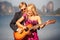blonde girl with guitar by guitarist on beach