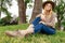 Blonde Girl in hat chilling in the park. Looking at camera and smile. Travel and active life concept. Outdoors