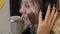 A blonde girl with headphones sings a song in a recording music studio at the microphone. 4k video format.